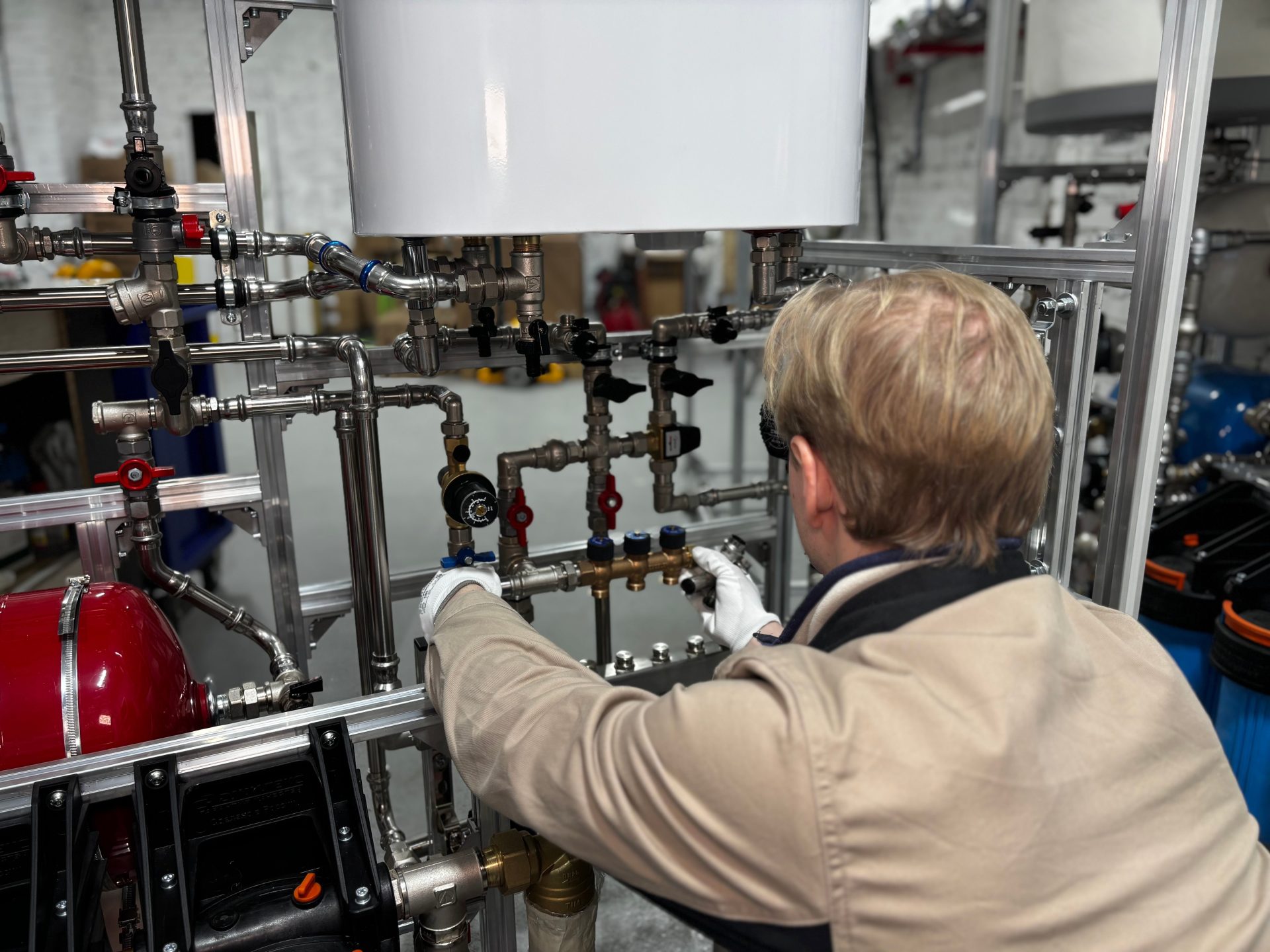 Ingénieur travaillant sur un réseau de tuyauterie industrielle dans une usine, pour le chauffage et le réglage de la production.