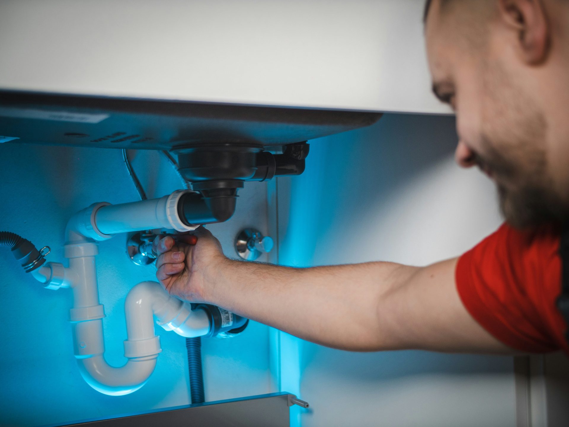 un homme travaillant sur une canalisation dans un mur
