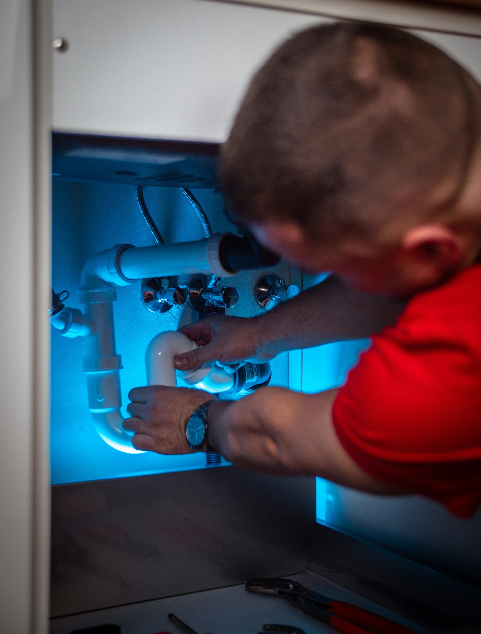 un homme travaillant sur une canalisation dans un placard